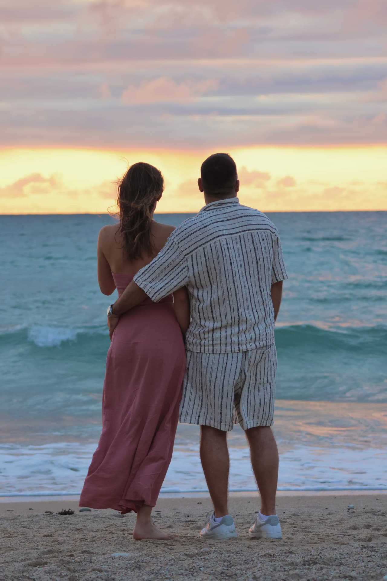 Couple enlacé de dos regardant le coucher de soleil sur la mer